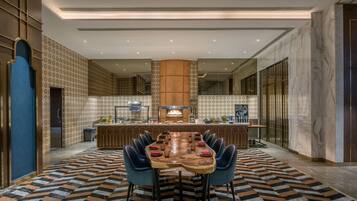 A modern dining area with a long wooden table, blue chairs, and a patterned floor.