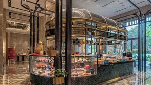 En moderne hotellobby med et centralt kaffestation, en glas elevator og udsigt til det fri.