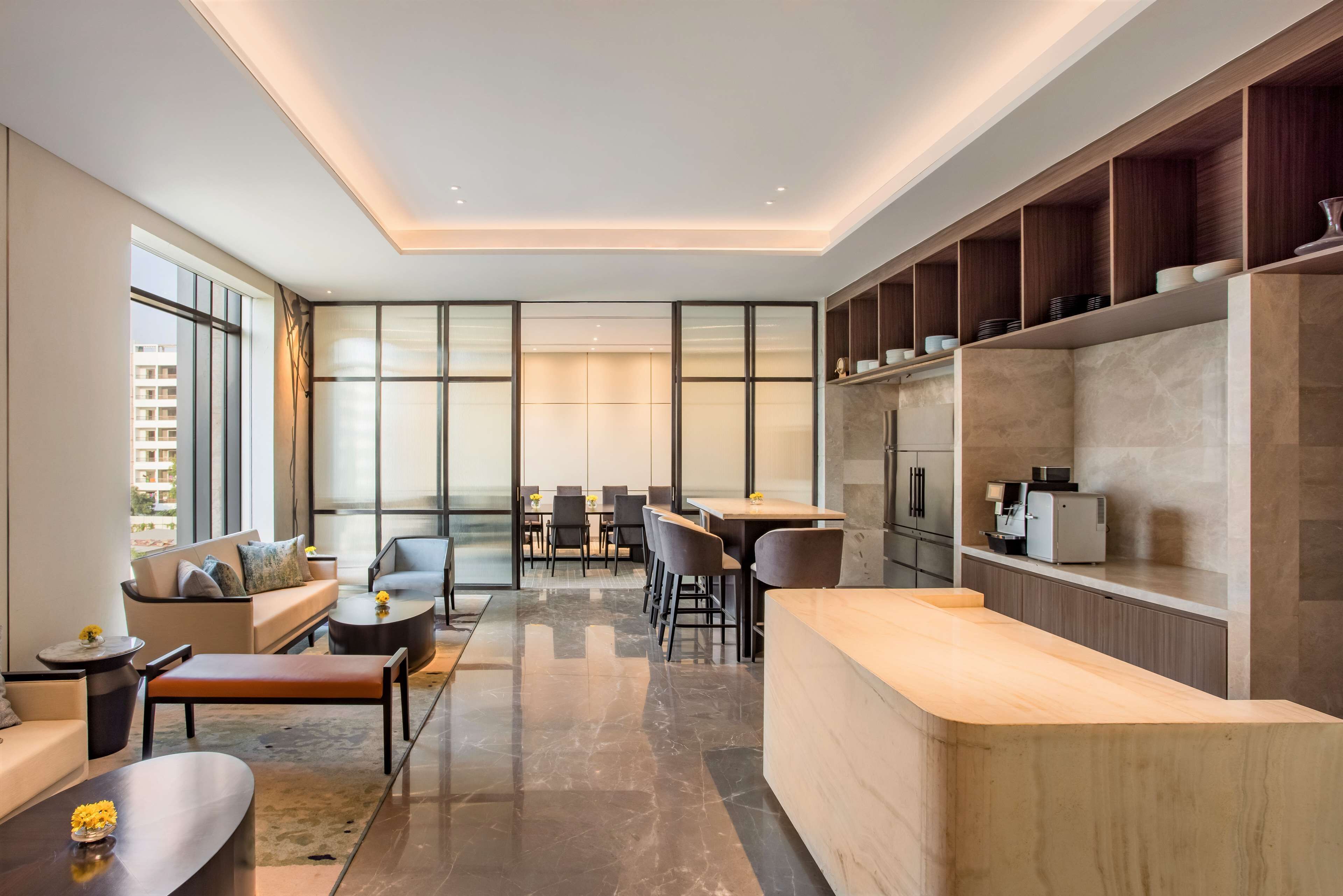 A modern living room with a sofa, coffee table, and dining area. There is a kitchen area with a countertop and cabinets.