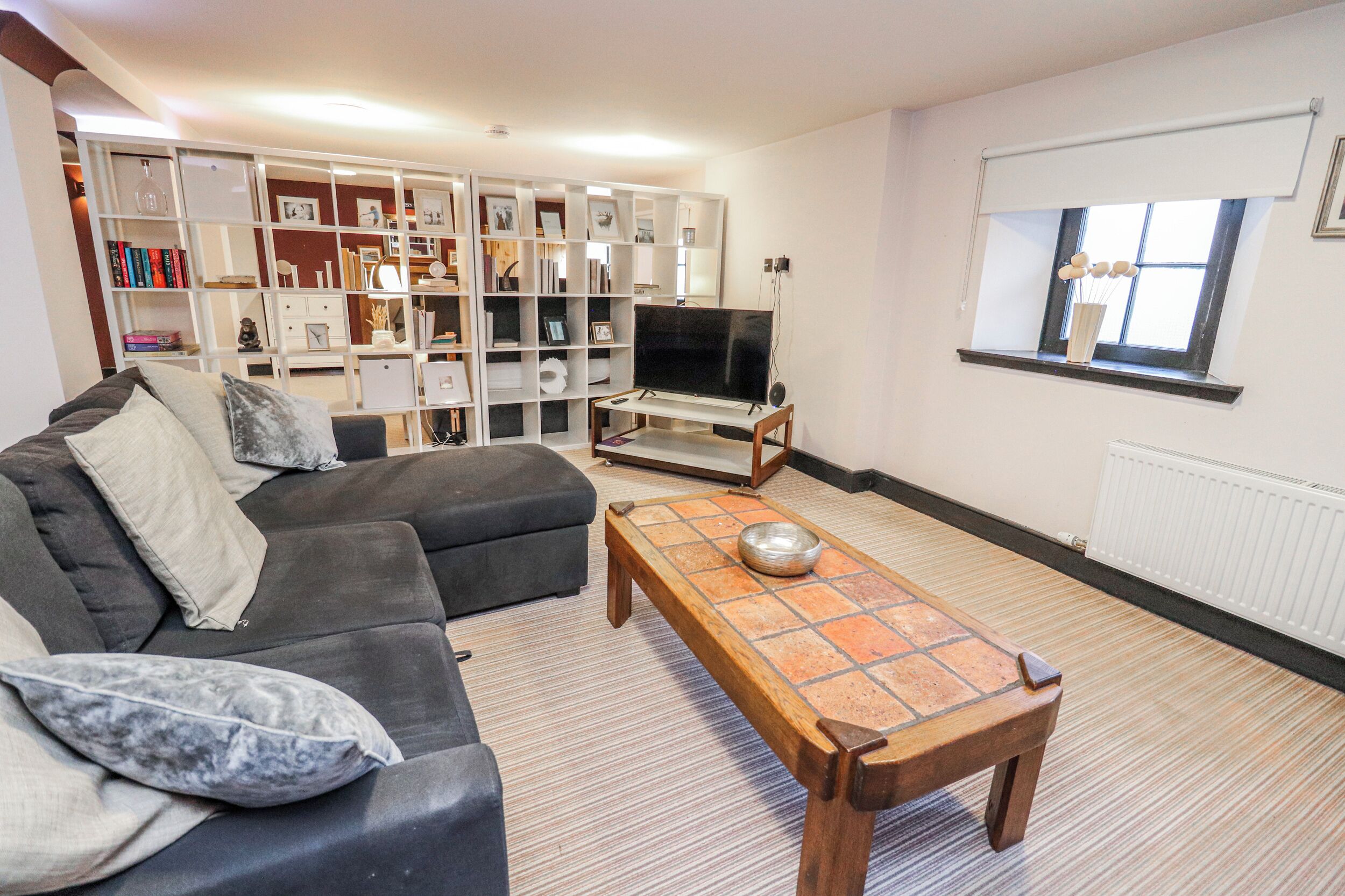 A living room with a sofa, a wooden coffee table, a television, and a bookshelf.