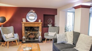 Una sala de estar con chimenea, dos sillones, un sofá y una mesa de centro.