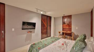 Un dormitorio moderno con cama, televisor montado en la pared, escritorio con silla y ventana con persianas de madera.