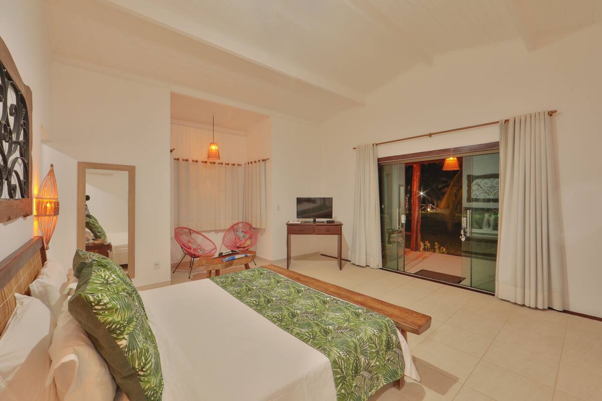 A hotel room with a bed, a desk, a TV, a chair, and a sliding glass door to the outside.