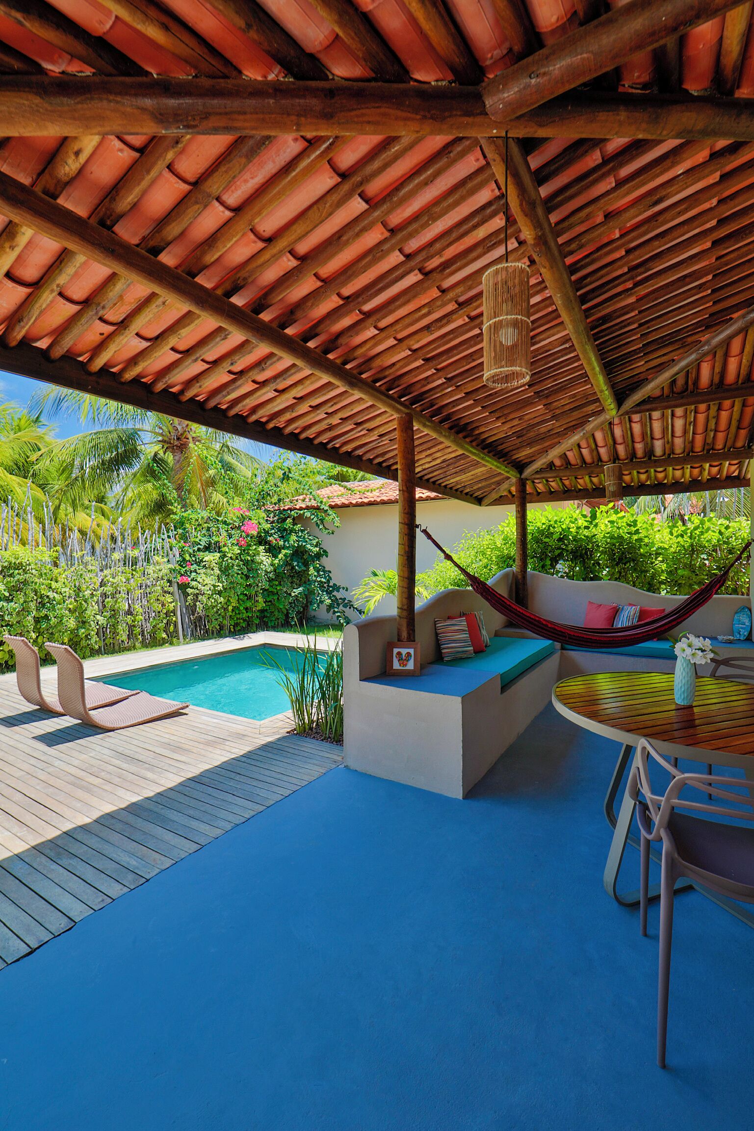 A covered outdoor area with a pool, seating, and a hammock.