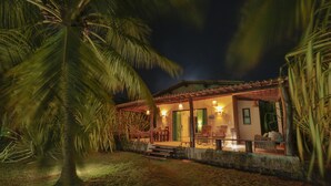 A house with a porch, outdoor seating, and a palm tree. - Villas Taturé (São Miguel dos Milagres)