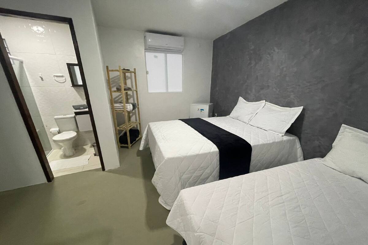 A hotel room with two beds, a bathroom, and a wardrobe.
