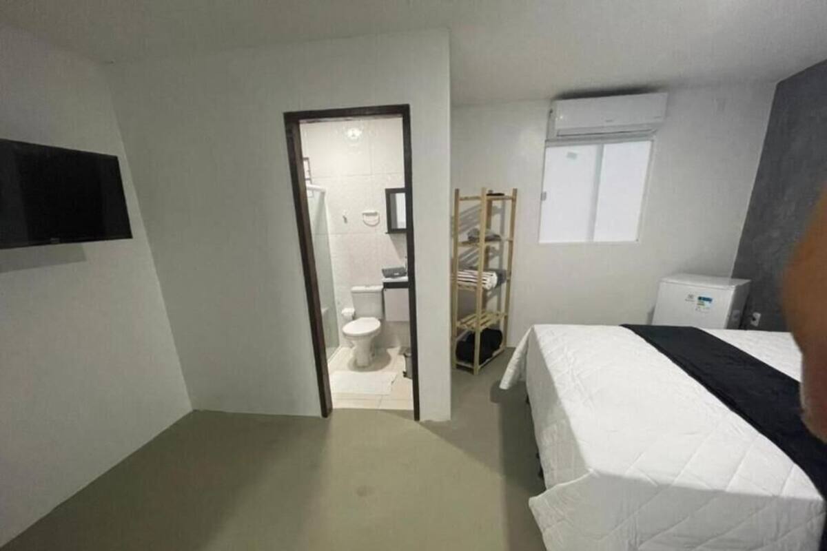 A hotel room with a bed, a TV, a wardrobe, and a bathroom visible through an open door.