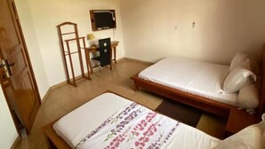 A bedroom with two beds, a desk, a chair, and a television.