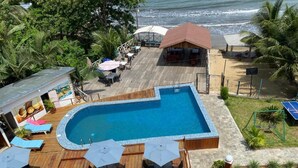 Una piscina con bordo in legno, lettini e ombrelloni.