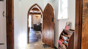 A hallway with wooden doors, a stone-tiled floor, a sofa, and a bookshelf. - Y Felin at Coed Cadw (Crymych)