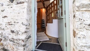 A rustic stone building with a wooden staircase leading to a lofted area. - Y Felin at Coed Cadw (Crymych)
