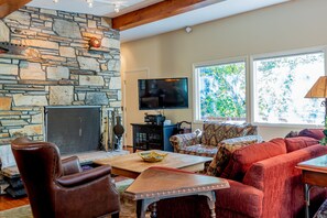 A cozy living room with a stone fireplace, comfortable seating, and a television. - Aspen Home - Pet Friendly, Private Hot Tub & Close to Bald Mountain Ski Lodge (Ketchum)