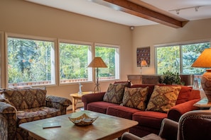 A cozy living room with a red sofa, patterned armchairs, and a wooden coffee table. - Aspen Home - Pet Friendly, Private Hot Tub & Close to Bald Mountain Ski Lodge (Ketchum)