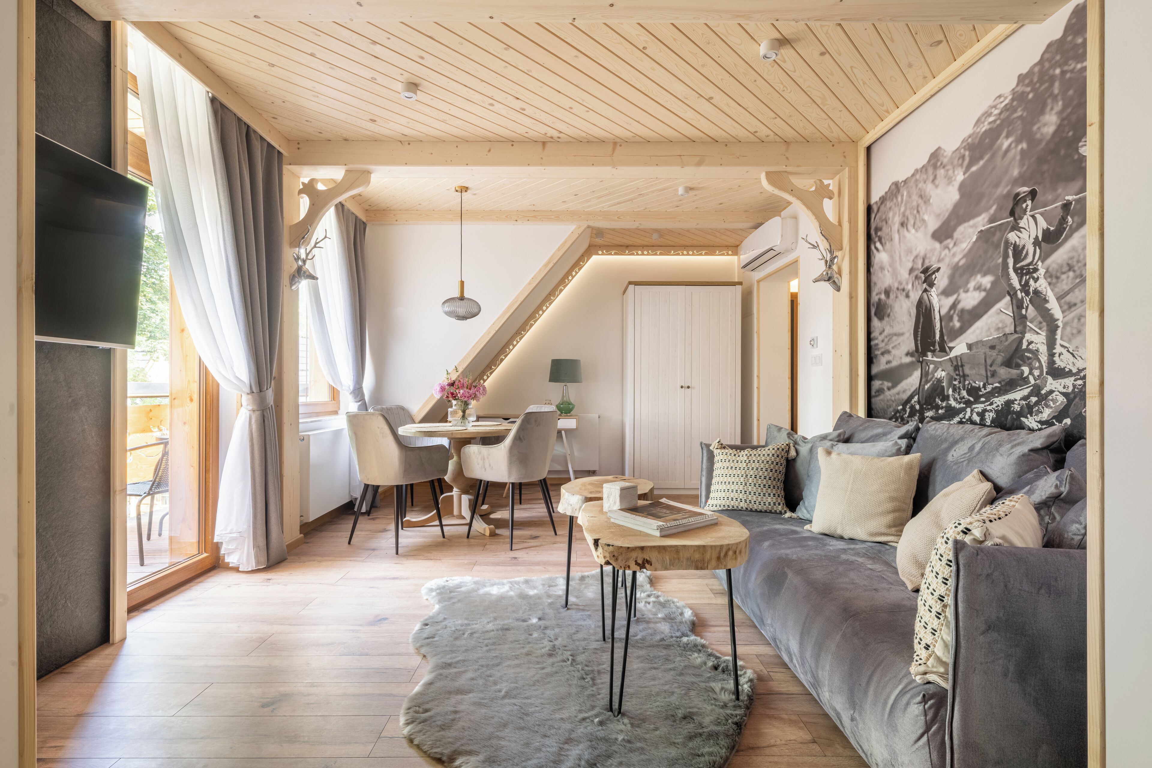 Ett modernt vardagsrum med en grå soffa, ett soffbord i trä och en matplats med ett bord och stolar.