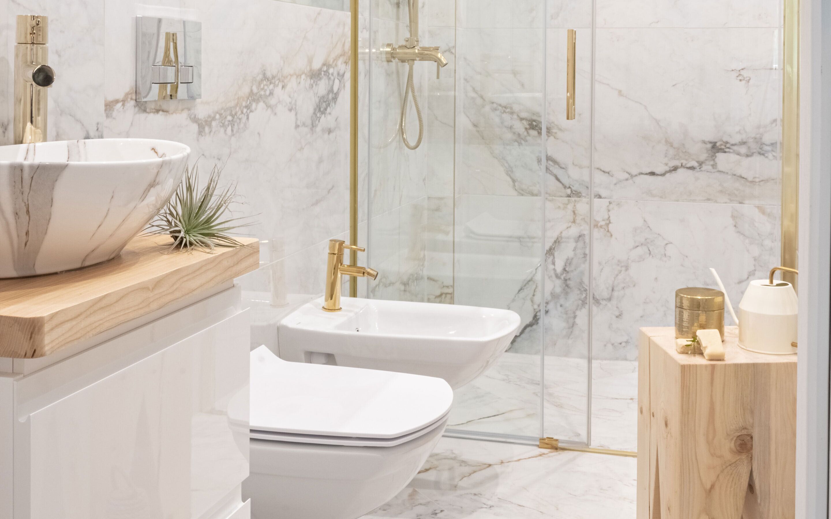 A modern bathroom with a white marble sink, a bidet, and a glass-enclosed shower area.