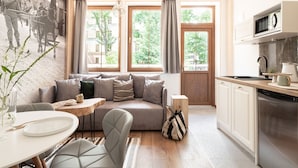 A cozy living room with a sofa, a dining table, and a kitchen area with a microwave and sink. - Apartamenty Villowe - Zakopane Centrum (Zakopane)