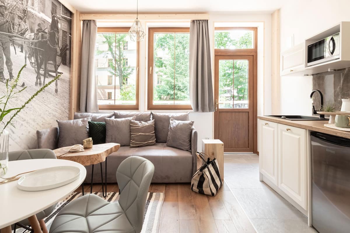 Een gezellige woonkamer met een bank, een eettafel en een keukenhoek met een magnetron en een spoelbak.