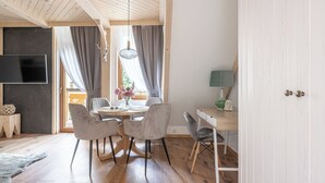 A dining area with a wooden table, grey upholstered chairs, and a hanging light fixture. - Apartamenty Villowe - Zakopane Centrum (Zakopane)
