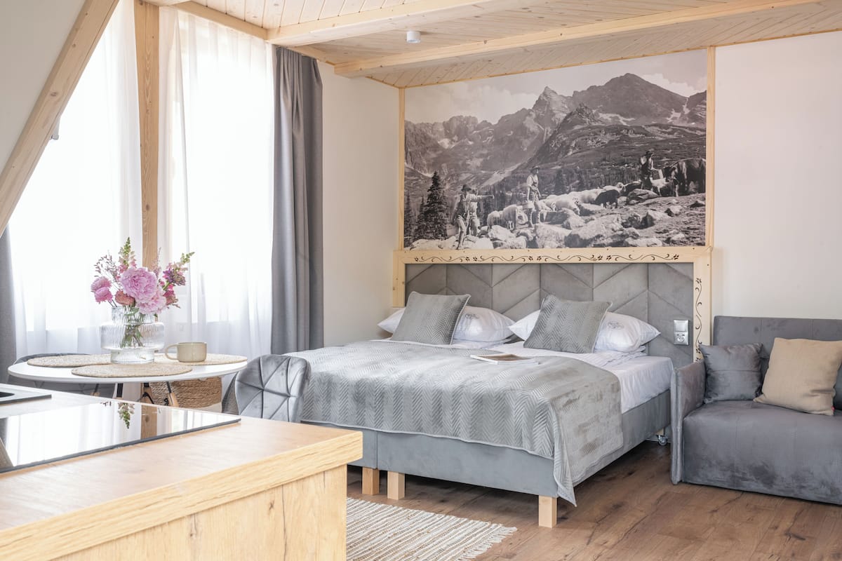 Een slaapkamer met een bed, een bank, een bureau en een groot muurschildering.