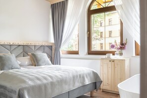 Een slaapkamer met een bed, een houten kast en een raam met gordijnen.