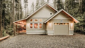 A cabin with a sloped roof, a covered porch, and a garage. - 52gs - Hot Tub - Wifi - Pets Ok - Wood Stove - Sleeps 6 2 Bedroom Home by RedAwning (Deming)
