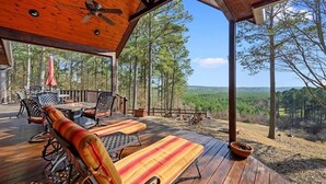 A wooden deck with outdoor furniture, a ceiling fan, and a view of a forested landscape. - Breathtaking Views, Seclusion, 4 Bedroom Luxury cabin on 5+ Acres! (Broken Bow)
