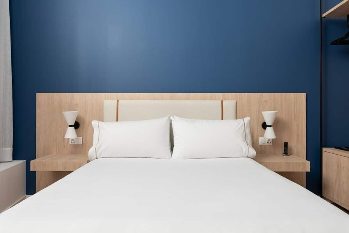 Una habitación de hotel con una cama grande, dos mesitas de noche y un cabecero de madera.