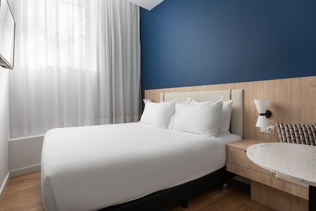 Una habitación de hotel con una cama grande, una mesita de noche y una mesa redonda.