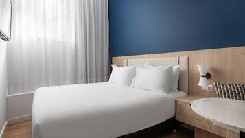 Una habitación de hotel con una cama grande, una mesita de noche y una mesa redonda.