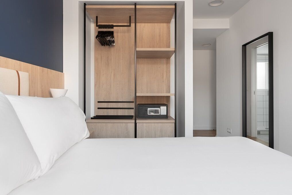 Een moderne slaapkamer met een bed, een inbouw kast met planken en een magnetron.