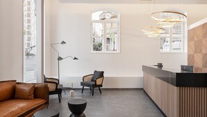 A modern reception area with a leather sofa, two chairs, a round table, and a reception desk. - Dorma Vigo (Vigo)