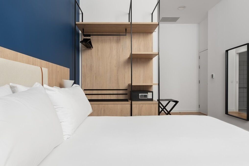 Ein modernes Hotelzimmer mit einem großen Bett, eingebauten Holzböden und einem kleinen Nachttisch.