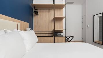Ein modernes Hotelzimmer mit einem großen Bett, eingebauten Holzböden und einem kleinen Nachttisch.