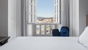 A hotel room with a large window, a bed, and a blue chair. - Dorma Vigo (Vigo)