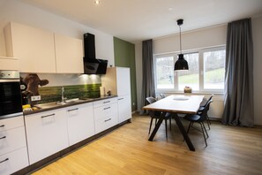 A modern kitchen with white cabinets, a wooden countertop, and a dining area with a table and chairs.