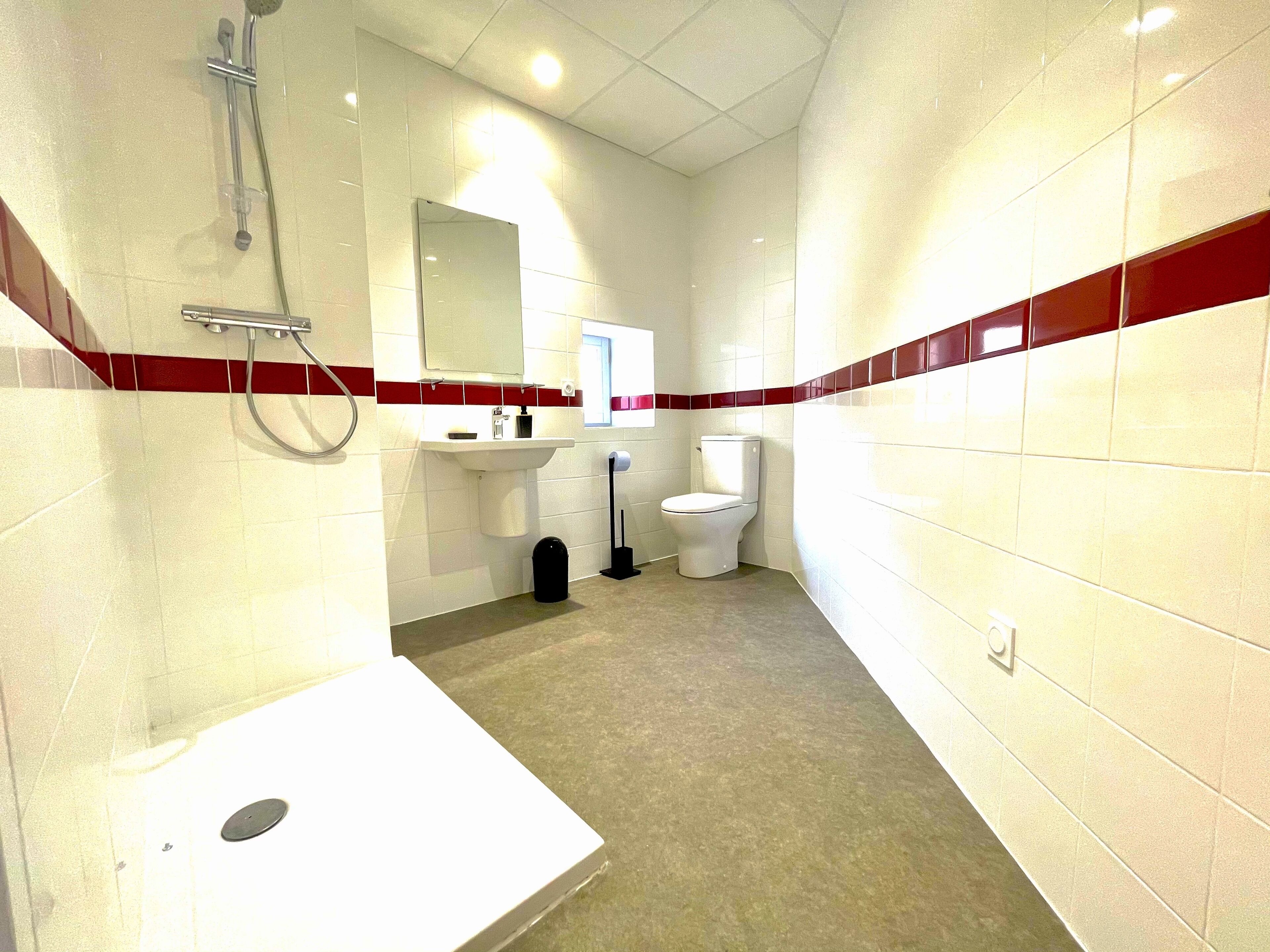 Un baño con azulejos blancos, un lavamanos, un inodoro y una ducha.