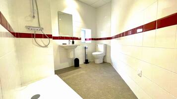 Un baño con azulejos blancos, un lavamanos, un inodoro y una ducha.