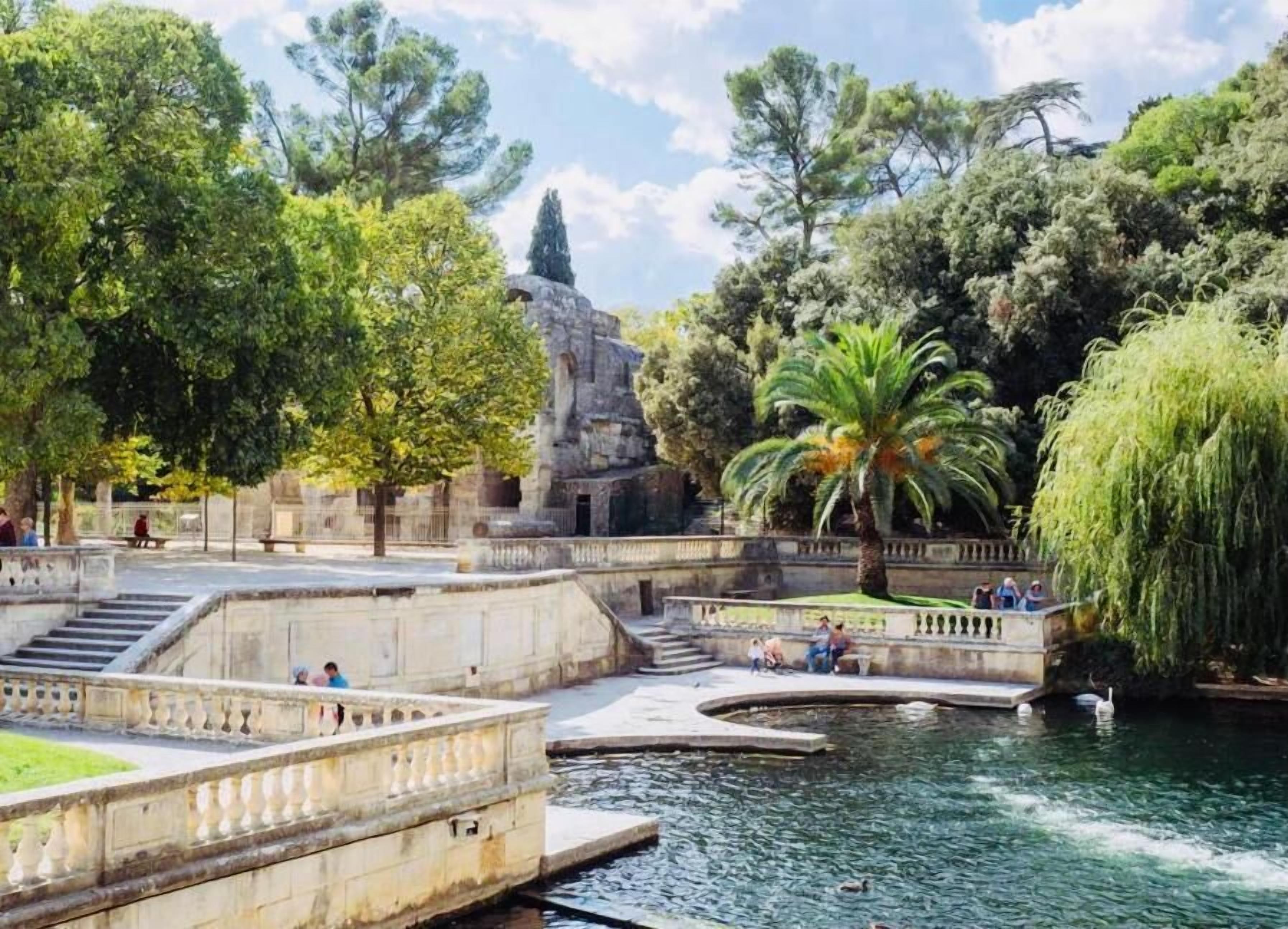 Un parque con una fuente, estructuras de piedra y árboles.