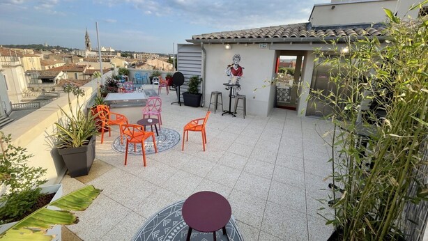 A rooftop terrace with orange chairs, a round table, and potted plants. - Hostel Flamingo Nîmes Centre Gare (Nîmes)