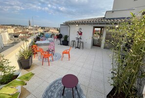 A rooftop terrace with orange chairs, a round table, and potted plants. - Hostel Flamingo Nîmes Centre Gare (Nîmes)