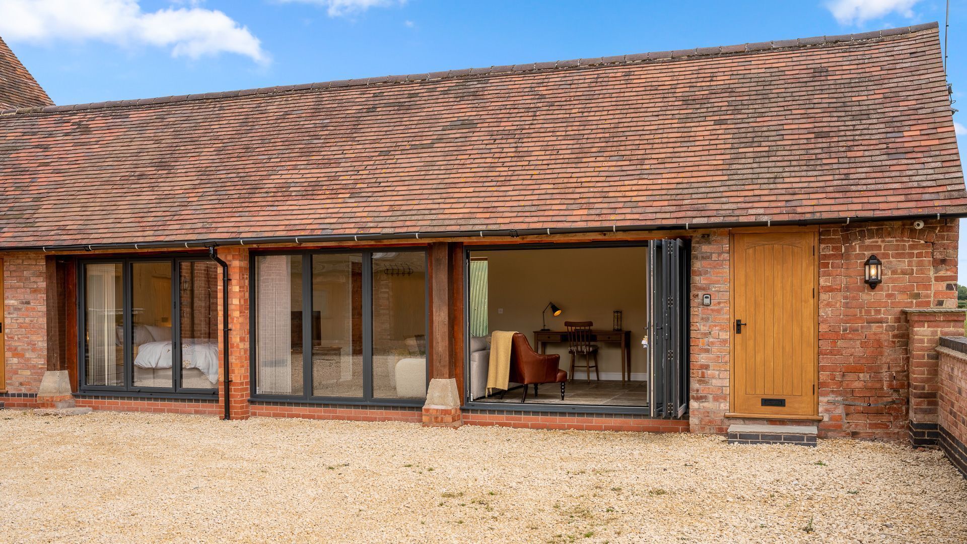 A two-story brick building with large sliding glass doors leading to a covered outdoor area.