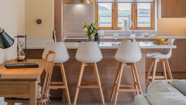 A modern kitchen with a central island, bar stools, and a dining table.