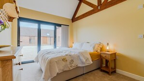 A bedroom with a bed, bedside table, and a view of the outside.