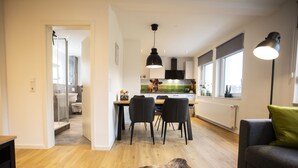 Cuina moderna amb zona de menjador, sofà i finestra gran.