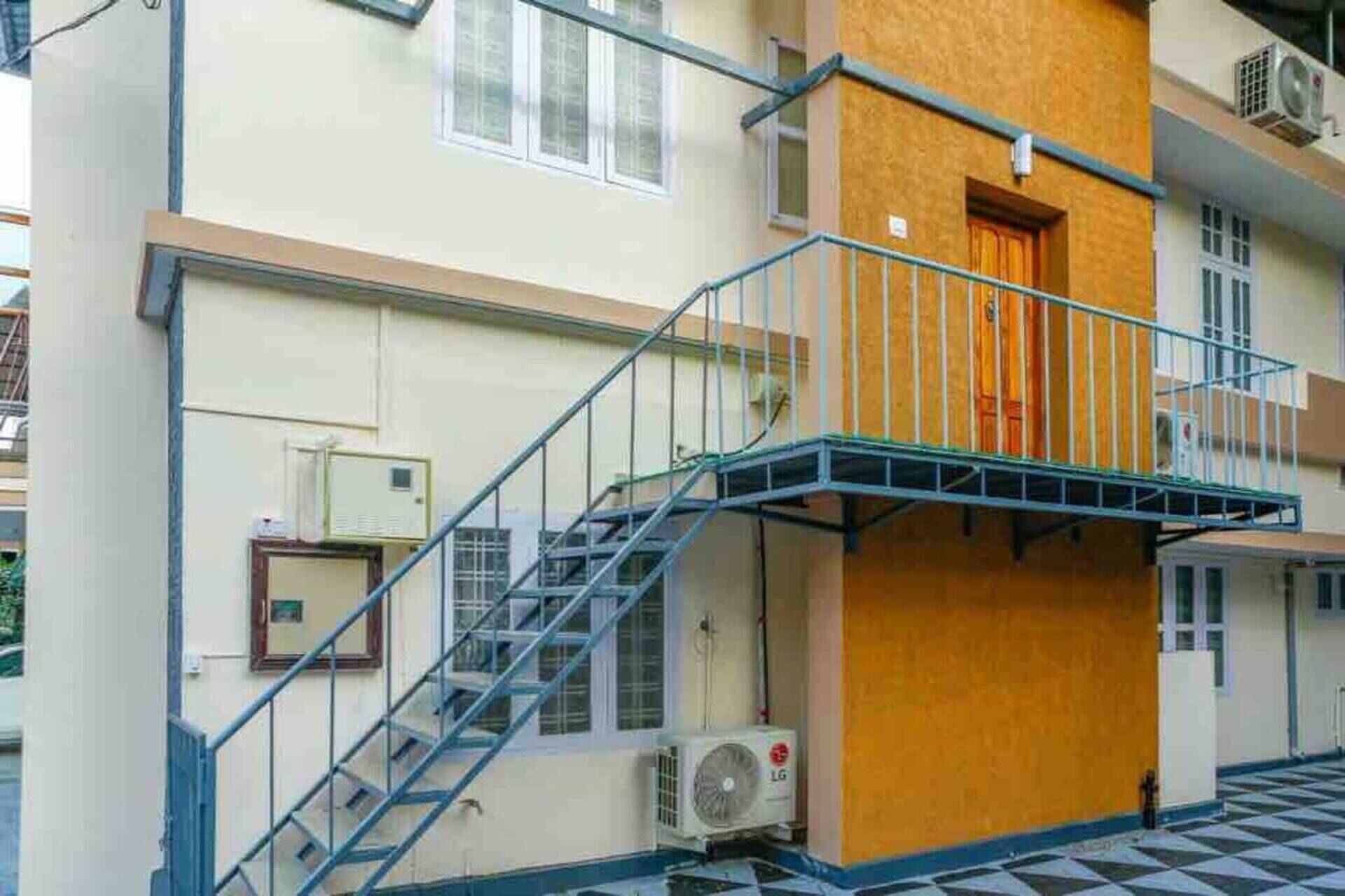 Een meerlaags gebouw met een blauwe metalen trap die naar een balkon leidt.