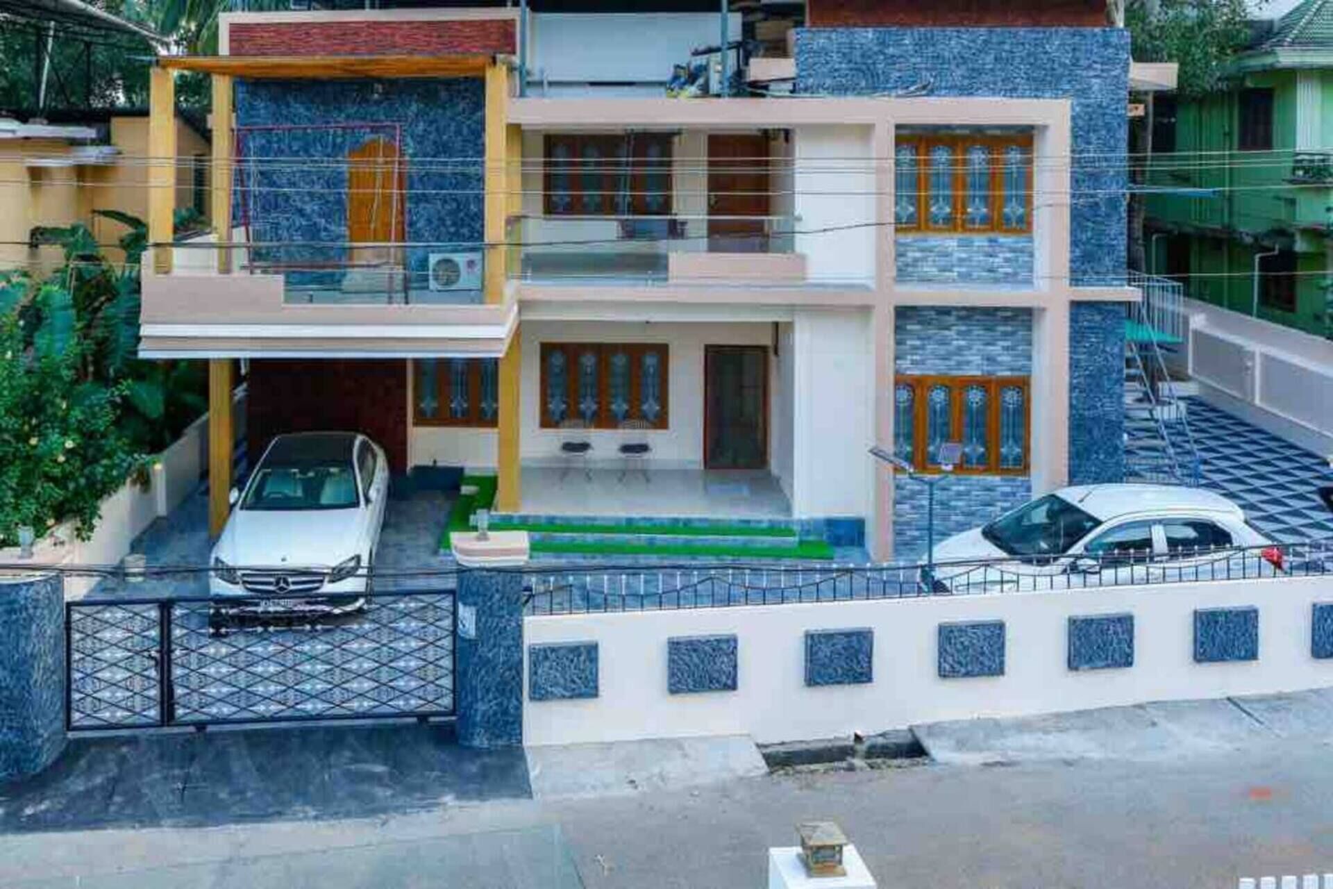 A multi-story residential building with a garage, two cars parked outside, and a gated entrance.