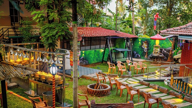 An outdoor seating area with wooden chairs, a swing set, and a fire pit.