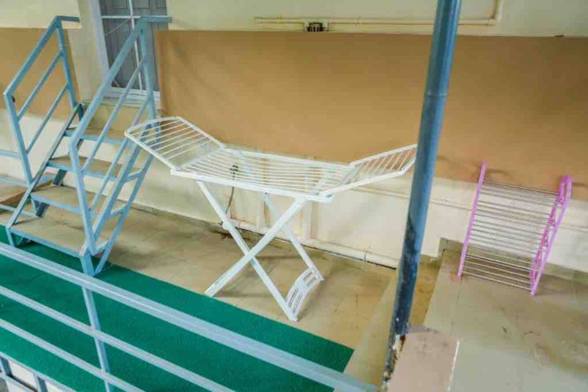 A room with a metal folding chair, a metal table, and a green mat on the floor.