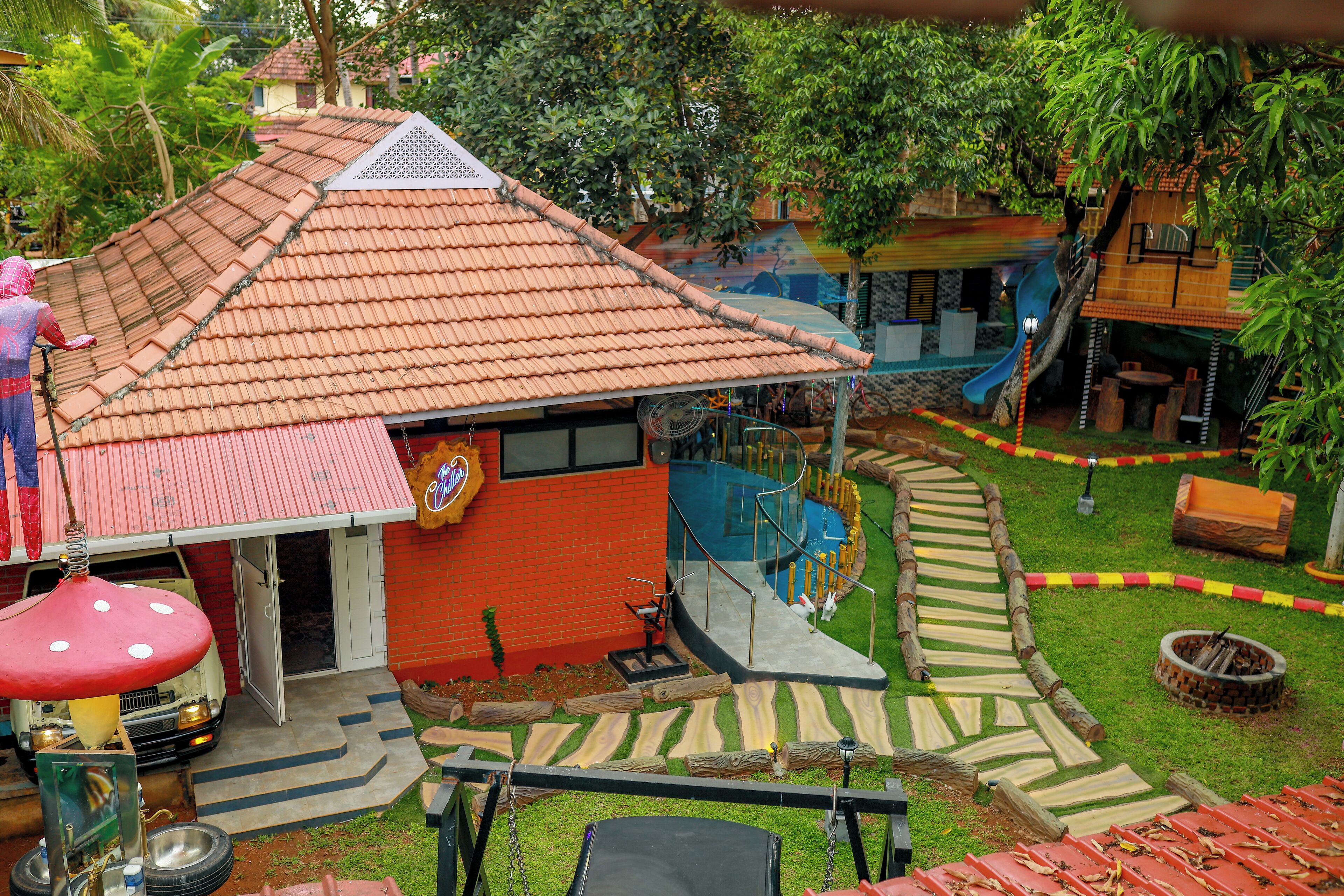 A house with a red roof, a small porch, and a slide leading to a wooden deck.