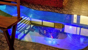A room with a glass-bottomed pool, a brick bench, and a motorcycle mounted on the wall.